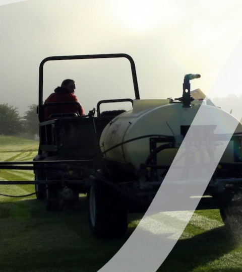 Self-propelled crop sprayer in a field at sunrise with long spray booms